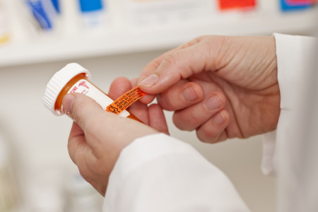 Pharmacist or doctor placing a warning label on a medicine bottle