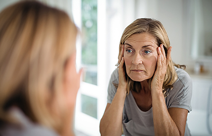 Woman looking at sagging skin in mirror