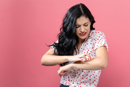 Young woman scratching her arm