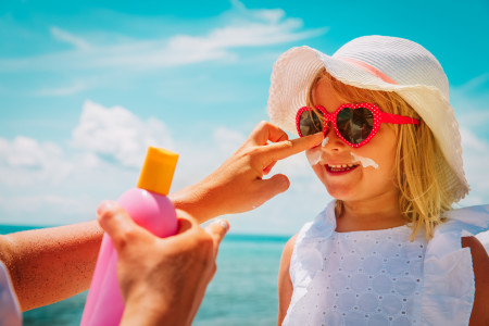 Mother applying sunscreen to girl's face