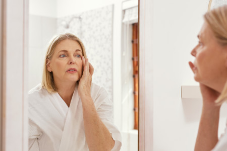 Image of a mature woman looking at herself in the bathroom mirror