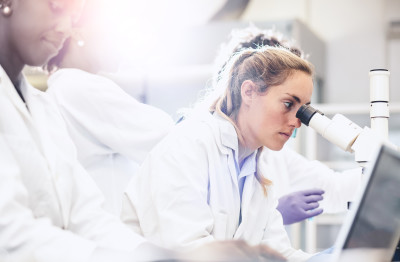 Doctors, one working with microscope.