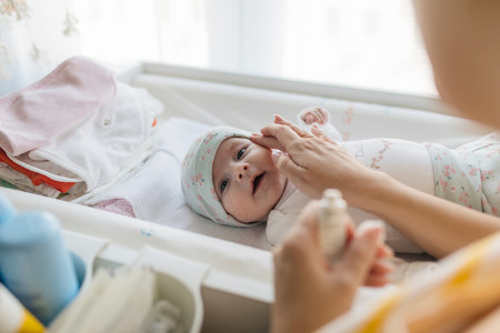 mother applying lotion on baby's face.