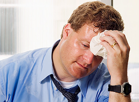 man wiping sweat from forehead