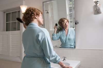 woman looking in mirror, brushing hair