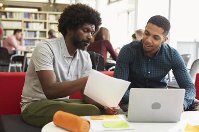 Two African American young adults working in library