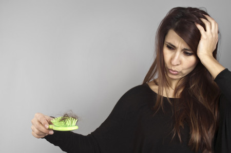 Woman looking at a hair brush with her hair in it