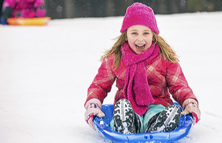 Girl on sled: Dry air, cold temperatures, and indoor heating can irritate your child’s skin, causing eczema to flare.