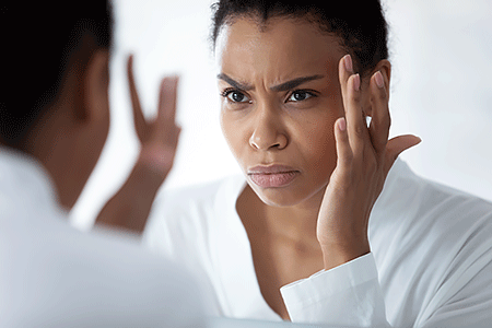 Woman looking in the mirror at frown lines