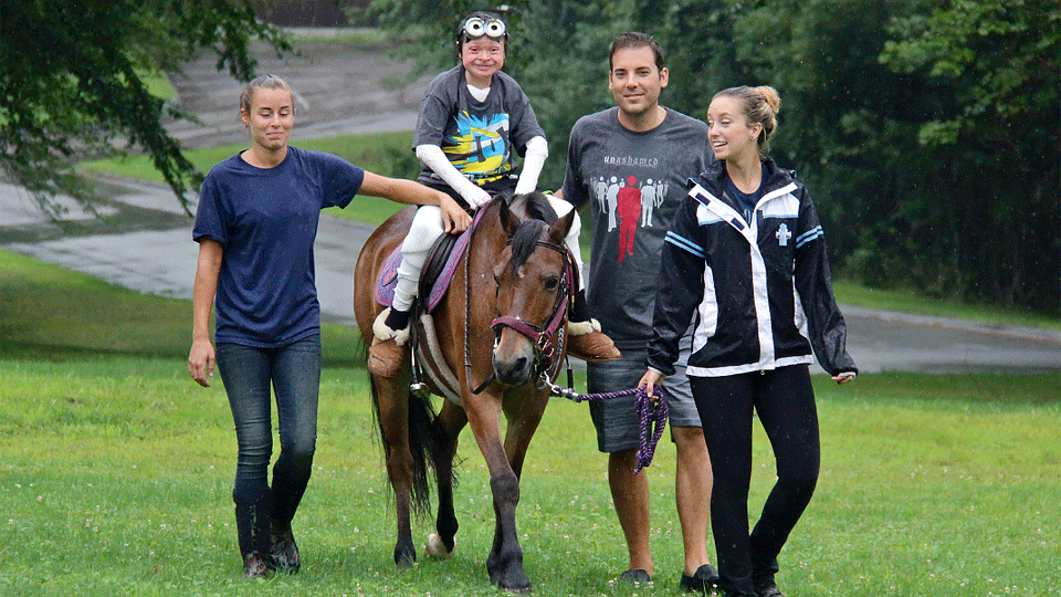 An AAD Camp Discovery participant horseback riding with camp volunteers