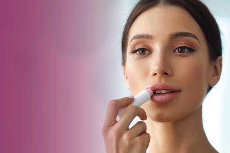 Woman applying lip balm to her chapped lips.