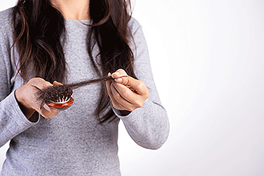 Woman pulling hair from hairbrush