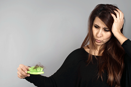 Woman holding hairbrush full of hair