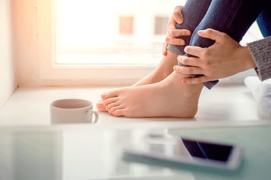 Feet of woman sitting on window sill