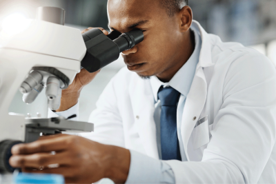 Male doctor looking into microscope.