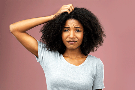 Woman with natural hair scratching psoriasis on her scalp