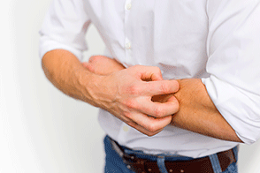 Man scratching dry, itchy skin on his arm