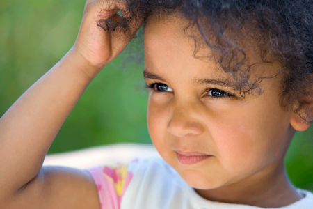 Headshot of toddler scratching eczema on her head.