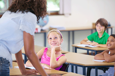 A young girl looking interested at the information being offered by her teacher in a classroom