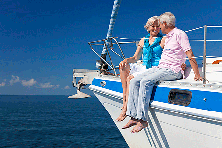 A happy senior couple sitting on the deck of a sail boat on a calm blue sea