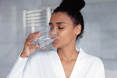 Woman swallowing pills with glass of water