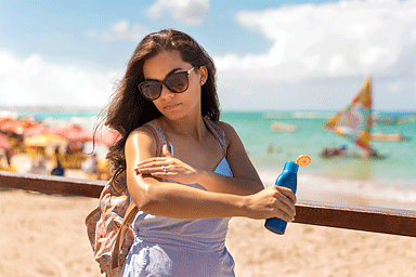 Mujer aplicando protección solar. (Woman applying sunblock protection.)