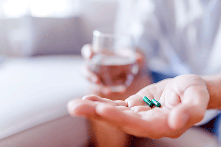 Man takes medicines with glass of water