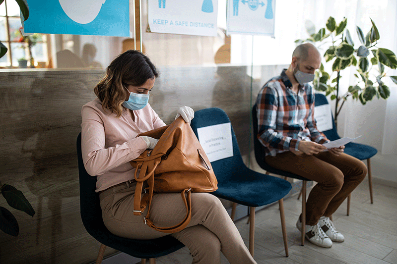 Patients with protective face masks keeping social distancing in doctor waiting room