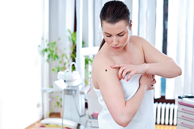 Woman looking suspicious mole in hospital room