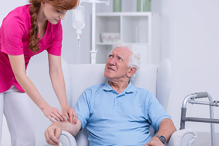 Nurse checking intravenous drip of senior patient