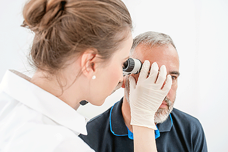 Dermatologist inspecting skin moles on a patient's face