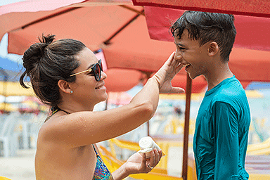 Mother putting sunscreen on boy.