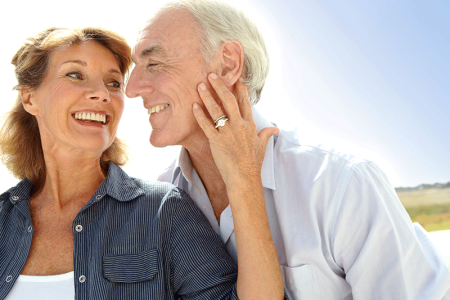 A happy maturely aged couple standing together outdoors.