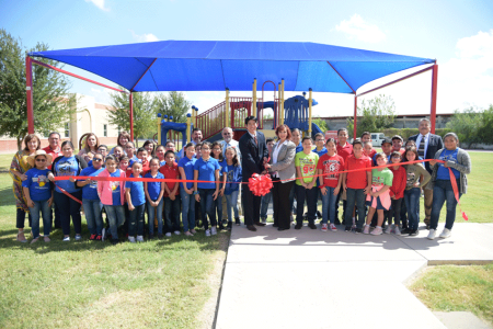 Children standing with dermatologist Connor Chan, MD, FAAD, in front of a shade structure