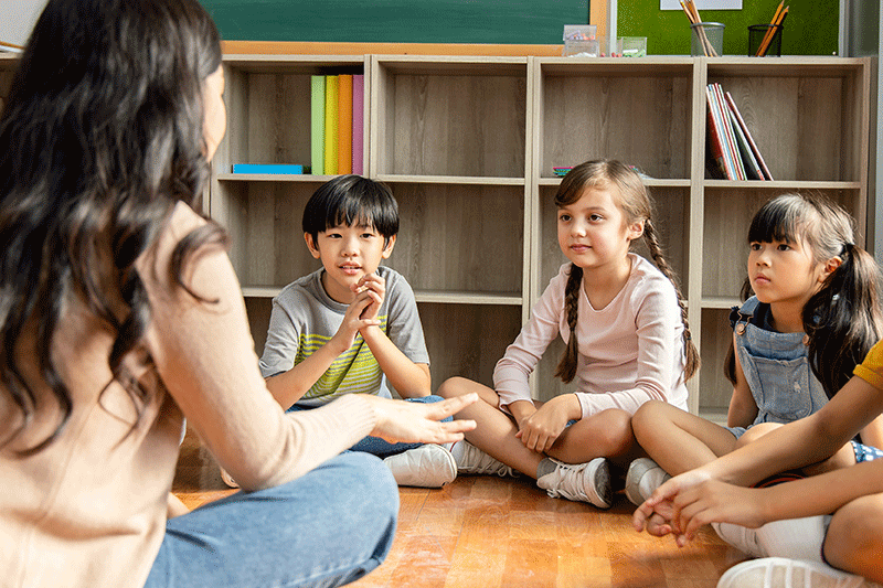 Students and teacher sitting in a circle on the floor