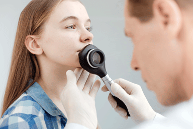 Dermatologist examining young girl's face skin using a dermatoscope